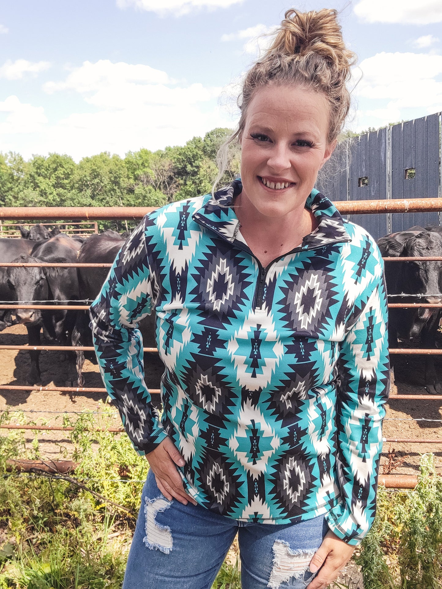 A woman wearing a teal and black geometric patterned pullover with a quarter zip.