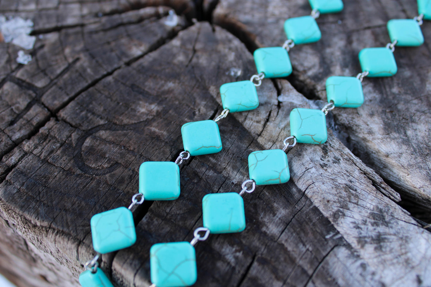 Turquoise square beads necklace on a wooden surface